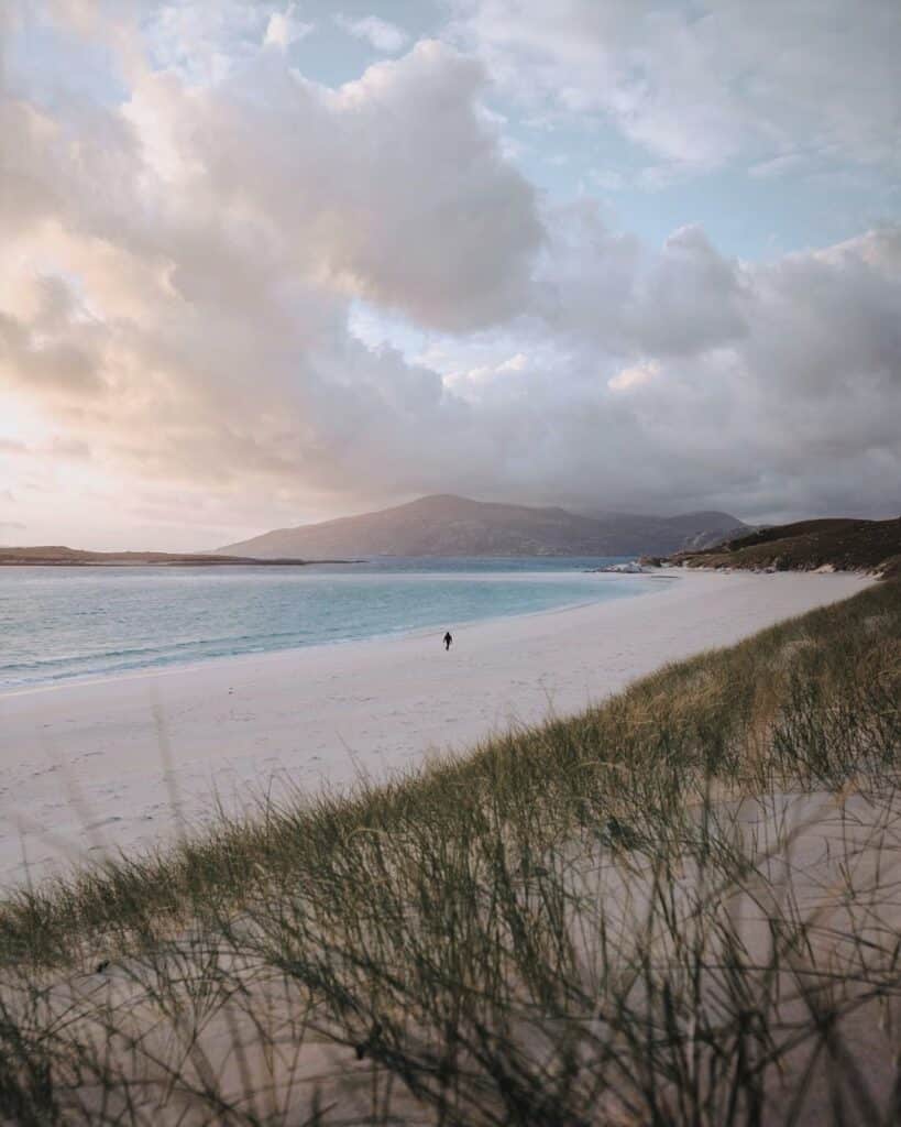 empty beach with man walking along it